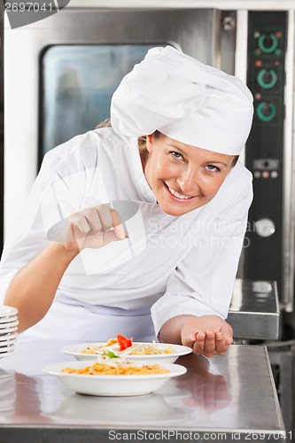 Image of Happy Chef Adding Spices To Dish