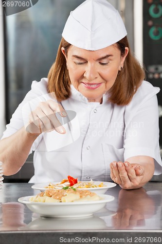 Image of Female Chef Adding Spices To Dish