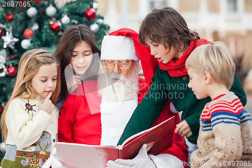 Image of Santa Claus And Children Reading Book