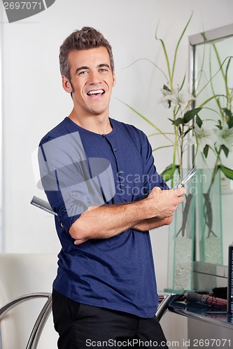 Image of Male Hairstylist Standing With Arms Crossed In Salon