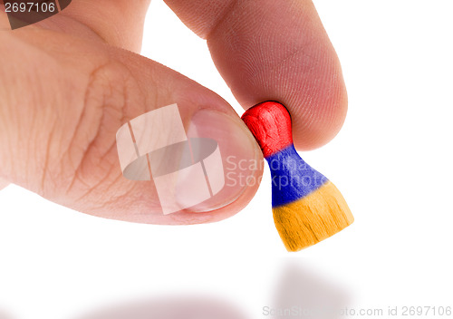 Image of Hand holding wooden pawn, flag painting, selective focus