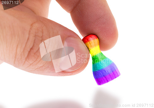 Image of Hand holding wooden pawn, flag painting, selective focus