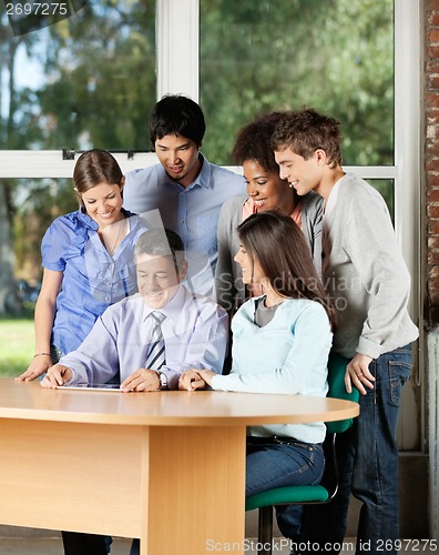 Image of Students And Teacher Looking At Digital Tablet In Classroom