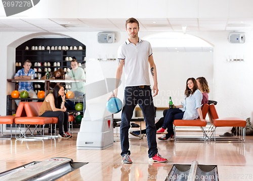 Image of Confident Man Holding Ball in Bowling Alley