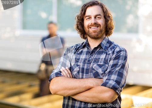 Image of Carpenter With Arms Crossed Standing At Construction Site