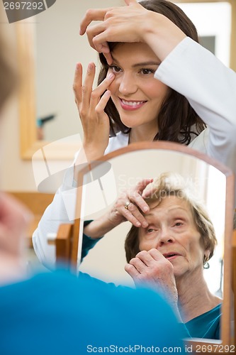 Image of Optometrist Teaching Senior Woman To Insert Contact Lens