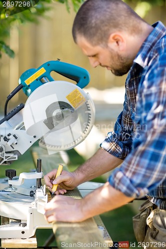 Image of Carpenter Marking On Wood With Pencil At Table Saw