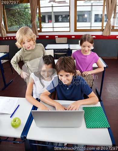 Image of Schoolchildren Using Laptop At Desk In Classroom