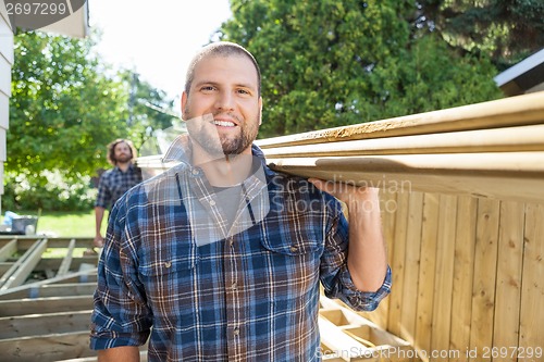 Image of Happy Carpenter And Coworker Carrying Lumbers At Construction Si