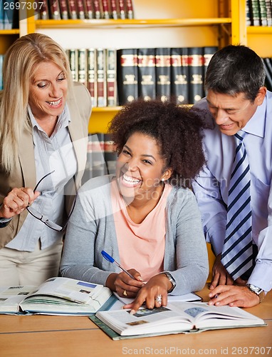 Image of Cheerful Student With Teachers Standing Besides Her In Library