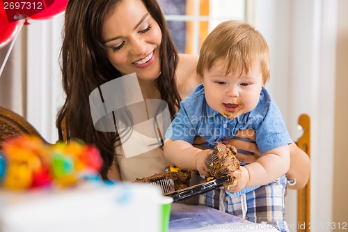 Image of Mother Holding Baby Boy Eating Cupcake