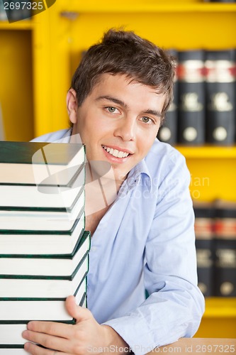 Image of Student With Stacked Books Smiling At Table In Library