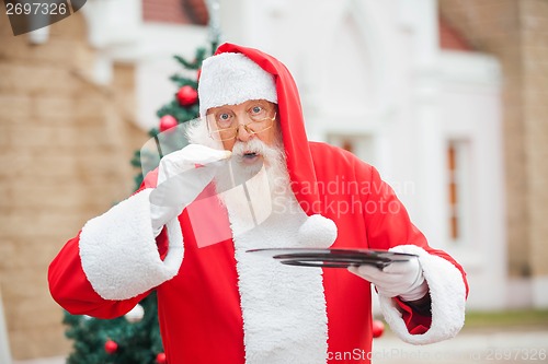 Image of Santa Claus Eating Cookie Against House