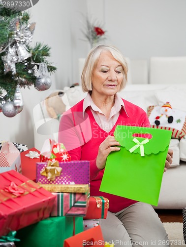Image of Woman Holding Bag While Sitting By Christmas Presents