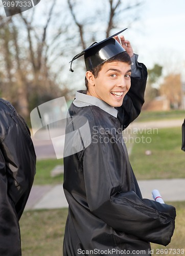 Image of Student In Graduation Gown Holding Certificate On Campus