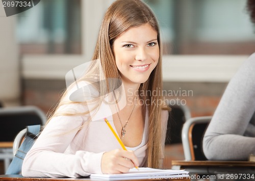 Image of College Student Sitting At Desk In Classroom