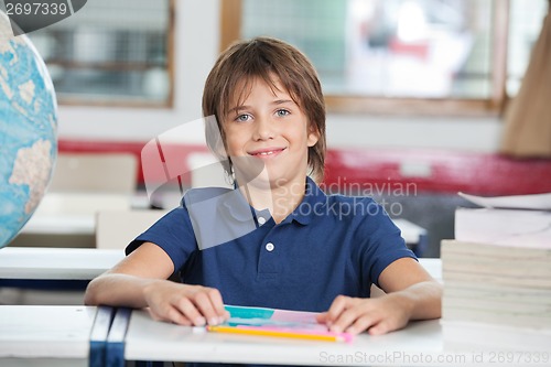Image of Schoolboy With Books And Globe At Desk