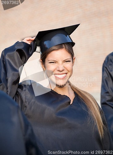 Image of Woman In Graduation Gown Holding Mortar Board On Campus