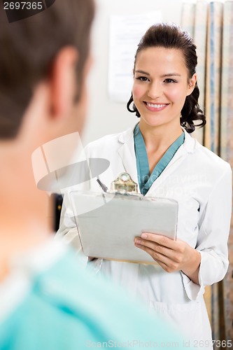 Image of Female Doctor With Clipboard Looking At Patient