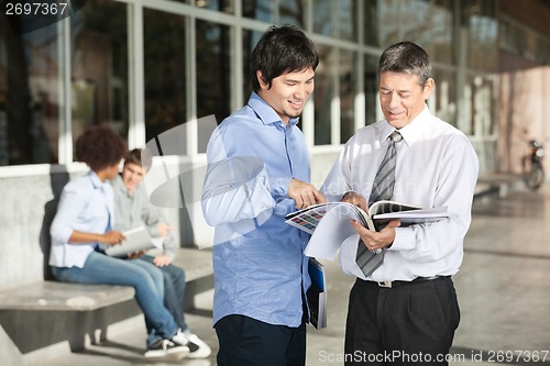 Image of Professor With Books Explaining Student On Campus