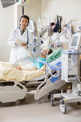 Image of Doctor Examining Patient's Test Report On Digital Tablet