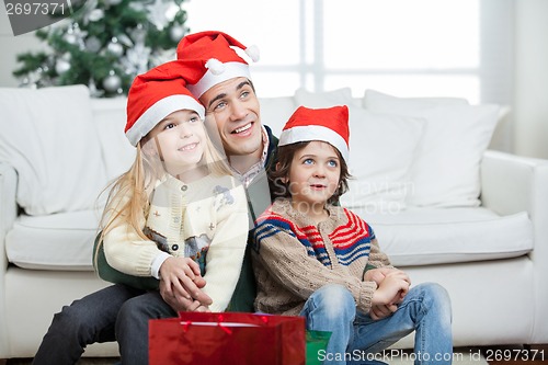 Image of Father And Siblings Wearing Santa Hats During Christmas