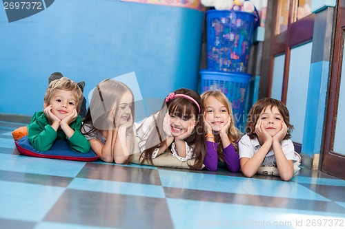 Image of Boys And Girls Lying On Floor In Kindergarten