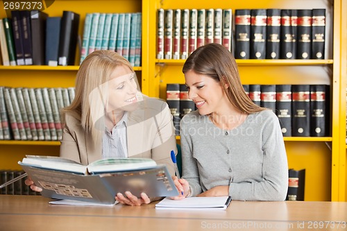 Image of Teacher Holding Book While Explaining Student In Library