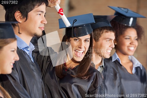 Image of Student Holding Certificate While Standing With Friends At Colle