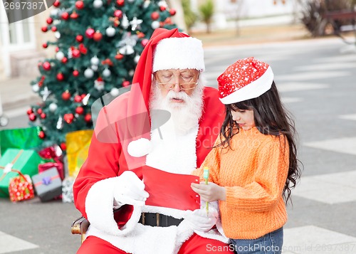 Image of Girl Showing Wish List To Santa Claus