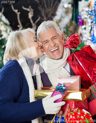 Image of Woman Kissing Happy Man With Christmas Presents