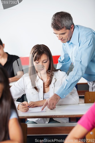 Image of Male Teacher Assisting Female Student At Desk