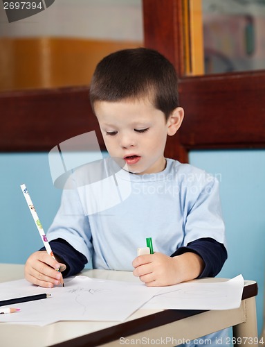 Image of Boy With Pencil Drawing On Paper In Classroom