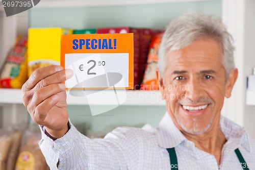 Image of Happy Male Owner Showing Discount Sign In Store