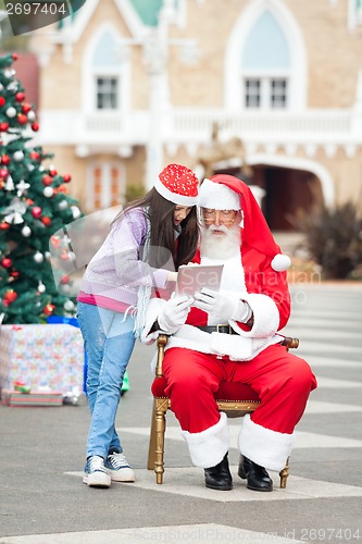 Image of Girl And Santa Claus Using Digital Tablet