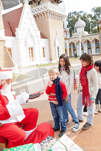 Image of Santa Claus Offering Biscuits To Children
