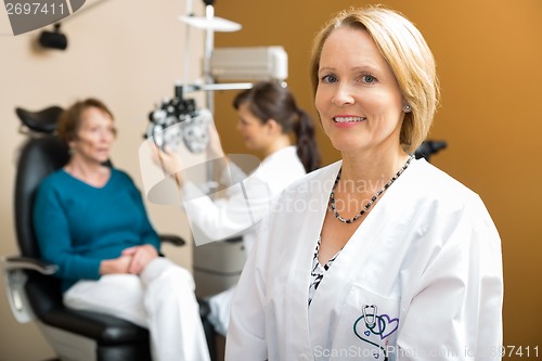 Image of Confident Eye Doctor With Colleague Examining Patient