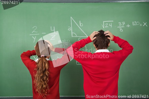 Image of Confused Schoolchildren Standing Against Board