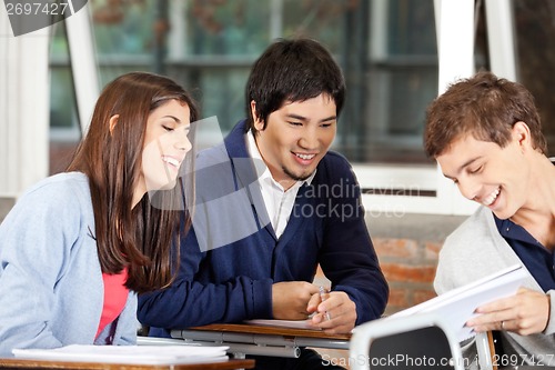 Image of Students Discussing Over Book In Classroom