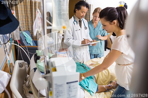 Image of Woman Looking At Patient While Doctor And Nurse Examining Report