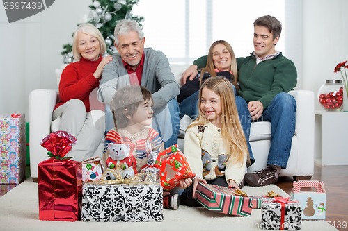 Image of Children With Christmas Presents While Family Sitting On Sofa