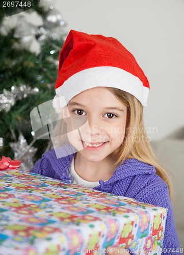 Image of Smiling Girl In Santa Hat Holding Christmas Gift