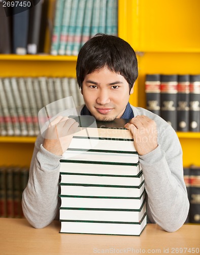 Image of Confident Man With Stacked Books Sitting In University Library