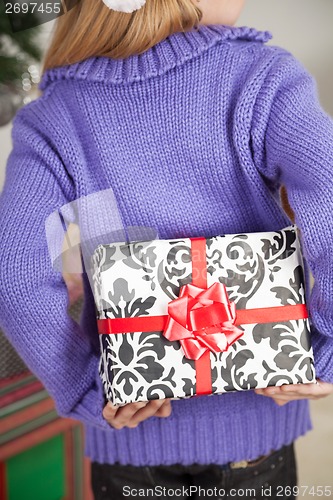 Image of Girl Hiding Christmas Gift Behind Back