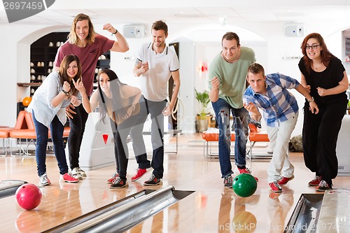 Image of Young Friends Bowling While People Cheering