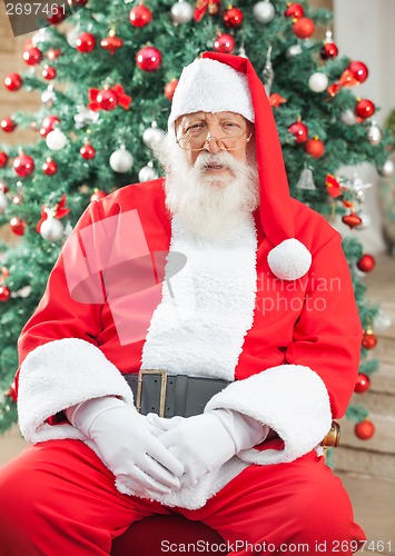 Image of Santa Claus Sitting Against Christmas Tree