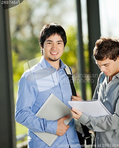 Image of Male Student With Friend Reading Book In Campus