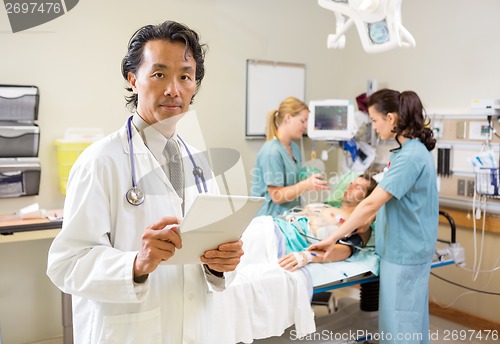 Image of Doctor Holding Digital Tablet While Nurses Treating Male Patient