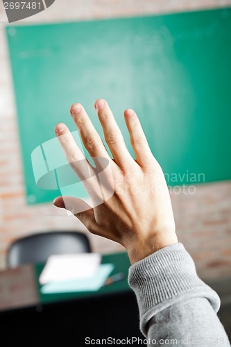 Image of Student's Hand Against Greenboard In Classroom