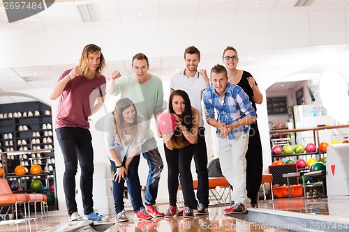 Image of Woman Bowling While Friends Motivating in Club